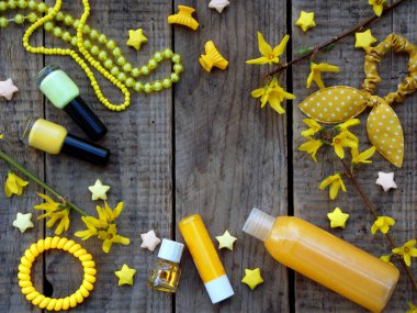 Composition of  yellow accessories for young girl or teenager. Nail polishes, lipstick, hair clips, bands, beads, bracelet, perfume and flowers. Top view on wooden background. clipart