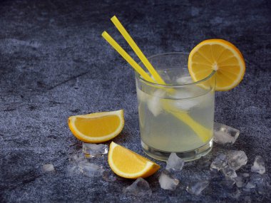 soğuk ev yapımı limonata limon dilimleri, buz küpleri ile koyu arka plan üzerine payet gözlük. Kopya alanı.