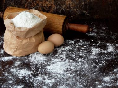 Buğday unu, yumurta ve oklava çanta bileşimi. Koyu arka plan üzerinde pişirme hamur yoğurma için hazırlık. Metin için yer