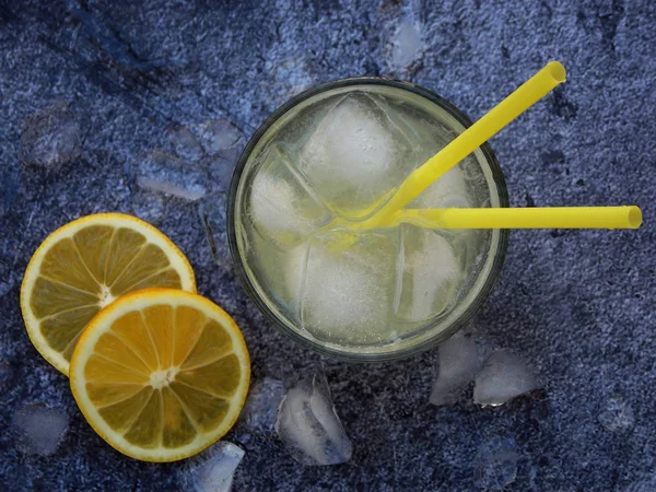 Glazen koude zelfgemaakte limonade met citroen segmenten, ijsblokjes en rietjes op donkere achtergrond. Kopiëren van ruimte. — Stockfoto