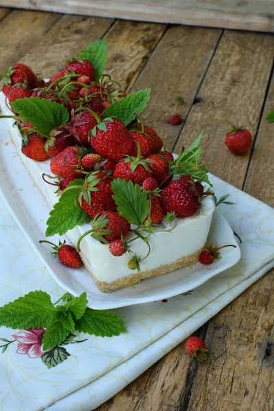 Köstlicher Käsekuchen mit Beeren, Bio-Erdbeeren aus dem Garten, leckerer und einfacher Kuchen auf Holzuntergrund. Kopierraum für Ihren Text — Stockfoto