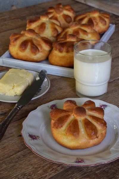 Panecillos de mantequilla en forma de flor servidos con mantequilla, cuchillo, vaso de leche sobre fondo de madera. Brioche recién horneado. Hornear en casa . — Foto de Stock