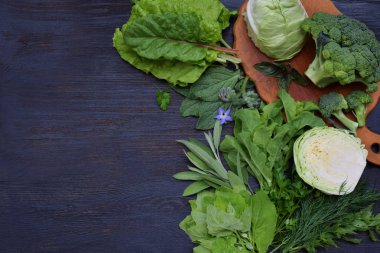 Karanlık bir arka plan kompozisyonu yeşil yapraklı sebze içeren folik asit, riboflavin, vitamin B9, B2, K, C - lahana, brokoli, pazı, marul, ıspanak, maydanoz, kereviz, dereotu, adaçayı. Üstten Görünüm.