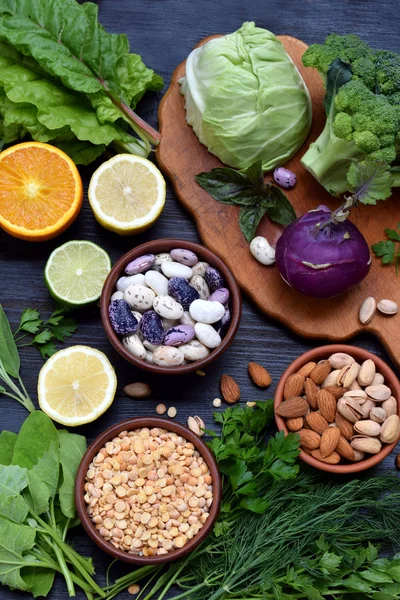 葉酸 (ビタミン B9)-緑の葉野菜、柑橘類、含有物の暗い背景に組成豆、エンドウ豆、ナッツ、酵母。平面図です。フラットを置く — ストック写真