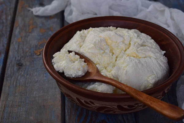 Коттеджный сыр из свёрнутого молока или йогурта в глиняной миске на деревянном фоне — стоковое фото