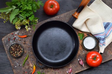 Bir boş siyah kızartma tavası, çeşitli sebze ve baharat ahşap arka plan üzerinde etrafında. Güveç hazırlanması