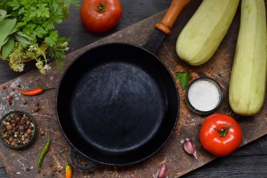 Bir boş siyah kızartma tavası, çeşitli sebze ve baharat ahşap arka plan üzerinde etrafında. Güveç hazırlanması