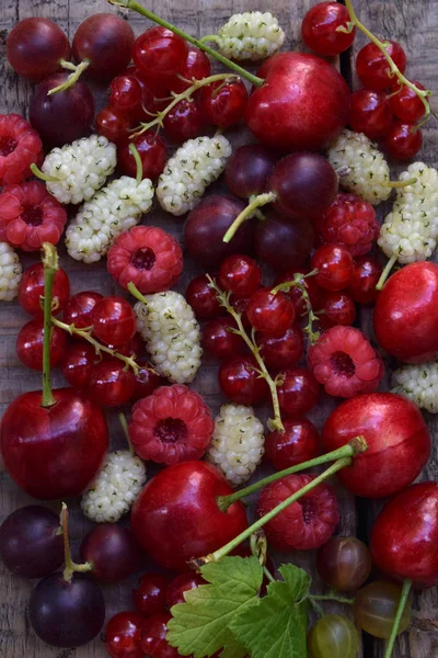 Rote Sommerbeeren: Kirsche, Maulbeere, Johannisbeere, Himbeeren auf einem hölzernen Hintergrund — Stockfoto