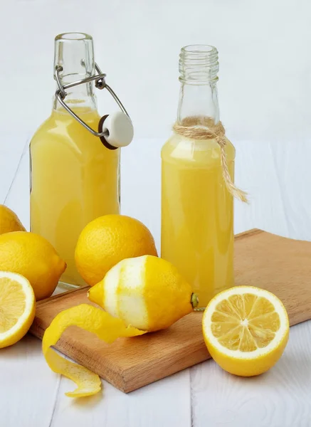 Succo di limone appena spremuto in bottiglia e limoni su fondo chiaro. Per bevande vitaminiche o cocktail. Concentrazione selettiva. Spazio per testo . — Foto Stock