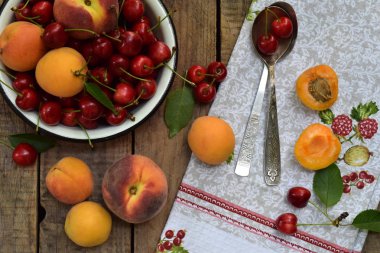 Taze meyve ve çilek ahşap arka plan üzerinde. Olgun tatlı kiraz ve kayısı kase mutfak masasında.