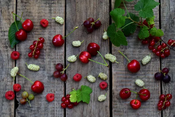 Röda sommarbär: mulberry, vinbär, körsbär, hallon på en trä bakgrund — Stockfoto