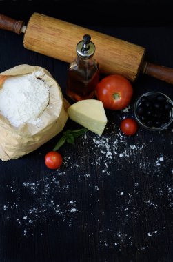 Buğday unu, petrol, domates, peynir ve oklava çanta bileşimi. Hamur yoğurma, pasta ya da koyu arka plan üzerinde pizza pişirme için hazırlık. Metin için yer