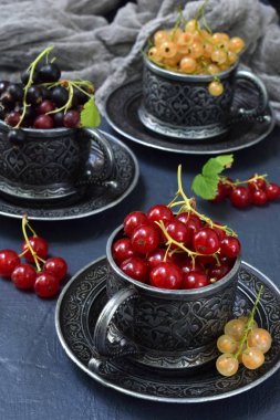 Taze olgun çilek bileşimi: kırmızı, siyah ve beyaz kuş üzümü bir koyu gri arka plan beton. Karanlık fotoğraf. Doğal ışık fotoğraf çekme. Senin metin için yer