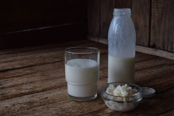 酸乳制品饮料或酸奶瓶中的，来自开菲尔粒和牛奶在木制的背景。与自然光拍摄 — 图库照片