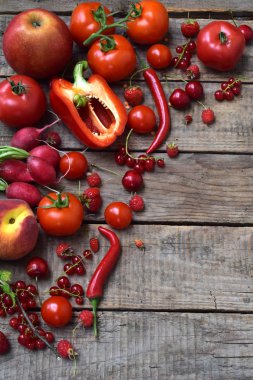 Kırmızı vejetaryen ürün bileşimi: meyve ve sebze ahşap arka plan üzerinde. Elma, domates, kuş üzümü, turp, biber, ahududu, tatlı kiraz. Sağlıklı gıda. Metin için yer kopyalayın