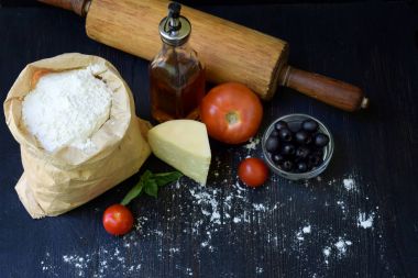 Buğday unu, petrol, domates, peynir ve oklava çanta bileşimi. Hamur yoğurma, pasta ya da koyu arka plan üzerinde pizza pişirme için hazırlık. Metin için yer