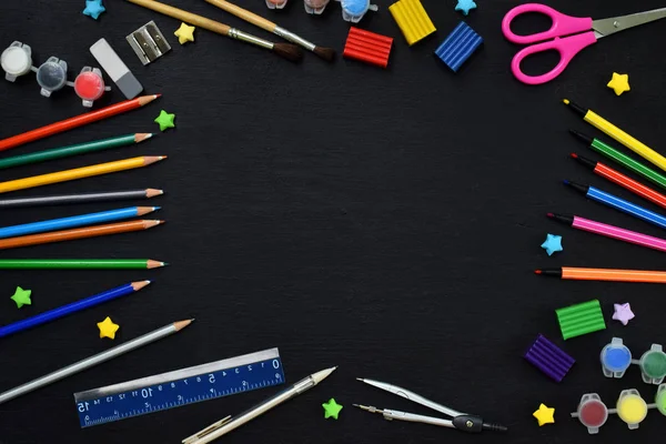 School accessoires en benodigdheden: potloden, stiften, verf, pennen, blackboard voor inscripties op een donkere achtergrond. Terug naar school. Bekijk van bovenaf. Plat leggen — Stockfoto