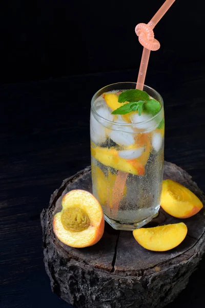Glas koude limonade voor zelfgemaakte perzik of mojito cocktail met munt op donkere achtergrond. Frisdrank drinken. Kopieer ruimte. Fotograferen met daglicht — Stockfoto