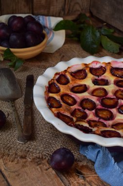 Ahşap arka plan üzerinde beyaz seramik formundaki Erik turtası. Homemade pişirme.