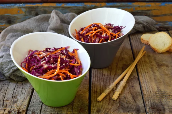 Salada de repolho roxo ou vermelho e cenouras polvilhadas com sementes de gergelim em um fundo de madeira. Alimentos saudáveis e vegetarianos — Fotografia de Stock