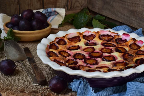 Ahşap arka plan üzerinde beyaz seramik formundaki Erik turtası. Homemade pişirme.