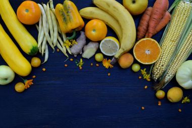 Sarı sebze ve meyve - muz, Mısır, limon, Erik, kayısı, biber, kabak, domates, kuşkonmaz fasulye, zencefil bileşimi. Sağlıklı gıda. Üstten Görünüm. Düz yatıyordu