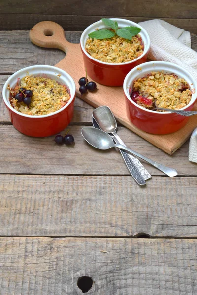 Meyve güveç ya da elma ve kahverengi Kupası ramekin ahşap arka plan üzerinde meyveleri ile kek. Uzay kopyalayın. Doğal ışık ile fotoğraf çekimi