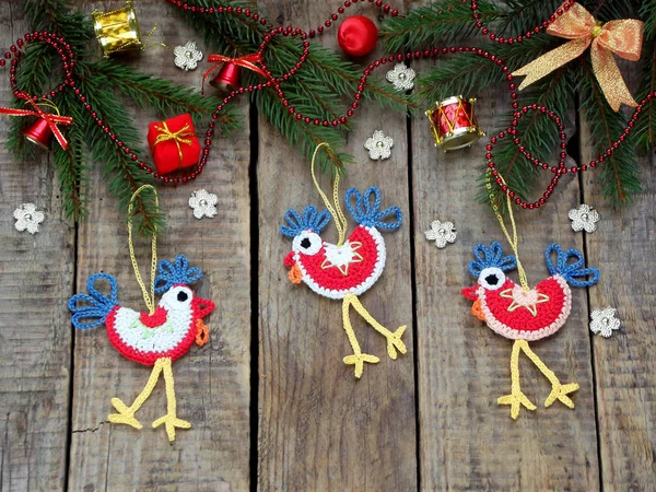 Crochet christmas decorations cockerels on wooden background — Stock Photo, Image