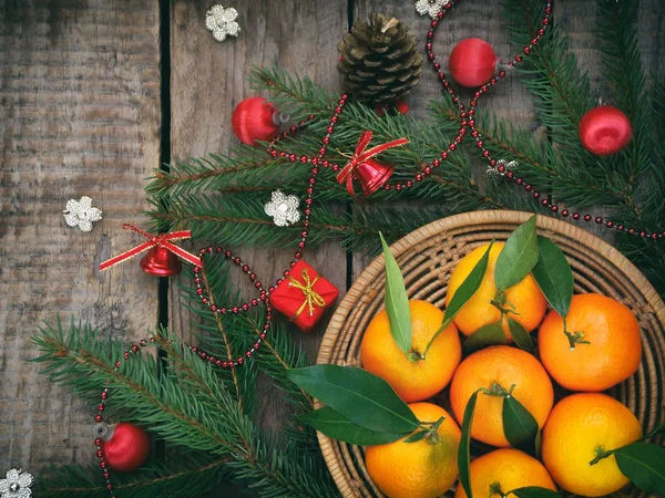 Panier de mandarines mûres, branches d'épinette et jouet de Noël sur un fond en bois. focus sélectif . — Photo