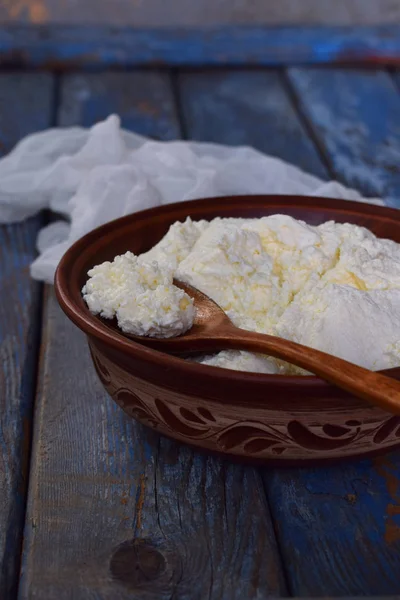 Коттеджный сыр из свёрнутого молока или йогурта в глиняной миске на деревянном фоне — стоковое фото