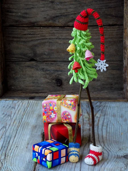 Creative Crochet Christmas trees with gifts on wooden background. New Year and Xmas card background. Copy space. Selective focus.