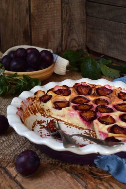 Ahşap arka plan üzerinde beyaz seramik formundaki Erik turtası. Homemade pişirme.