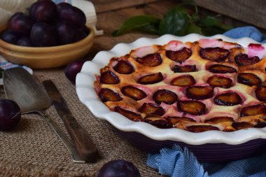 Ahşap arka plan üzerinde beyaz seramik formundaki Erik turtası. Homemade pişirme.