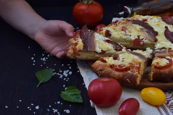 Домашняя вкусная пицца с сыром, помидорами и ветчиной прошутто на тёмном деревянном фоне . — стоковое фото