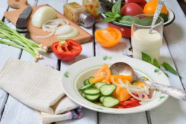 Vegetarischer, gesunder Salat mit frischem, reifem Sommergemüse: Tomaten, Gurken, Paprika und Zwiebeln auf hellem Holzgrund — Stockfoto