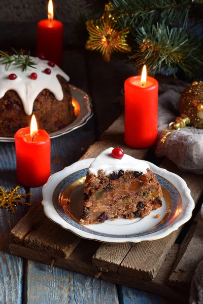 Pudín tradicional inglés de Navidad al vapor con bayas de invierno, frutos secos, nuez en un ambiente festivo con árbol de Navidad y vela encendida. Pastel de frutas — Foto de Stock