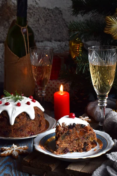 Traditioneller englischer Weihnachtspudding mit Winterbeeren, getrockneten Früchten, Nuss im festlichen Rahmen mit Weihnachtsbaum, brennender Kerze und Glas Weißwein, Champagner. Obstkuchen — Stockfoto