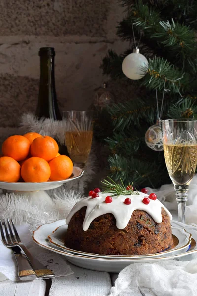 Traditioneller englischer Weihnachtspudding mit Winterbeeren, Trockenfrüchten, Nuss im festlichen Rahmen mit Weihnachtsbaum, Mandarinen und einem Glas Weißwein, Champagner. Obstkuchen — Stockfoto