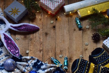 Kavramsal kış görüntüsü. Noel çerçeve hediyeler, Xmas süslemeleri, mittens ile rahat, ahşap arka plan üzerinde çikolatalar. Uzay kopyalayın. Metin için yer