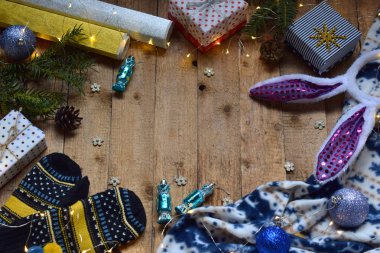 Kavramsal kış görüntüsü. Noel çerçeve hediyeler, Xmas süslemeleri, mittens ile rahat, ahşap arka plan üzerinde çikolatalar. Uzay kopyalayın. Metin için yer