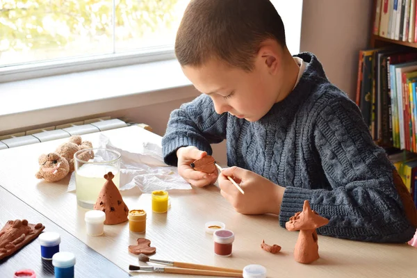 Niño haciendo juguetes de cerámica, pinta un juguete de cerámica de barro con gouache. Apoyo a la creatividad, aprendizaje por hacer, proyecto de bricolaje, artesanía. Concepto de educación y desarrollo de niños dotados . —  Fotos de Stock