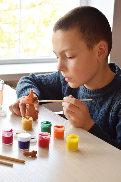 Niño haciendo juguetes de cerámica, pinta un juguete de cerámica de barro con gouache. Apoyo a la creatividad, aprendizaje por hacer, proyecto de bricolaje, artesanía. Concepto de educación y desarrollo de niños dotados . —  Fotos de Stock