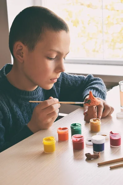 Niño haciendo juguetes de cerámica, pinta un juguete de cerámica de barro con gouache. Apoyo a la creatividad, aprendizaje por hacer, proyecto de bricolaje, artesanía. Concepto de educación y desarrollo de niños dotados . —  Fotos de Stock