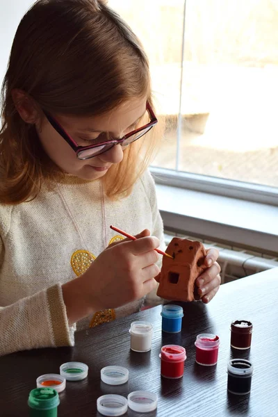 Chica haciendo juguetes hágalo usted mismo, pinta un juguete de cerámica de barro con gouache. Ocio creativo interior para niños. Apoyo a la creatividad, aprendizaje por hacer, proyecto de bricolaje, artesanía. Clase magistral de arte . —  Fotos de Stock