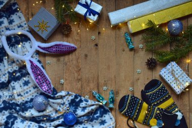 Kavramsal kış görüntüsü. Noel çerçeve hediyeler, Xmas süslemeleri, mittens ile rahat, ahşap arka plan üzerinde çikolatalar. Uzay kopyalayın. Metin için yer