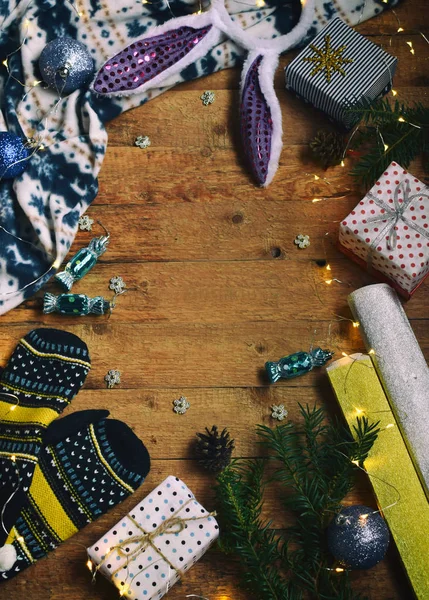 Immagine concettuale invernale. Accogliente cornice di Natale con regali, decorazioni natalizie, guanti, caramelle su sfondo di legno. Ricevuto. Posto per testo — Foto Stock