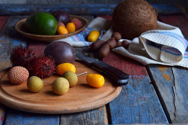 Смесь спелых тропических фруктов с маракуйей, кумкватом, личи, рамбутаном, тамариндой, авокадо, кокосом, драконьим глазом на деревянном фоне. Фон суперпитания. Вегетарианская еда — стоковое фото
