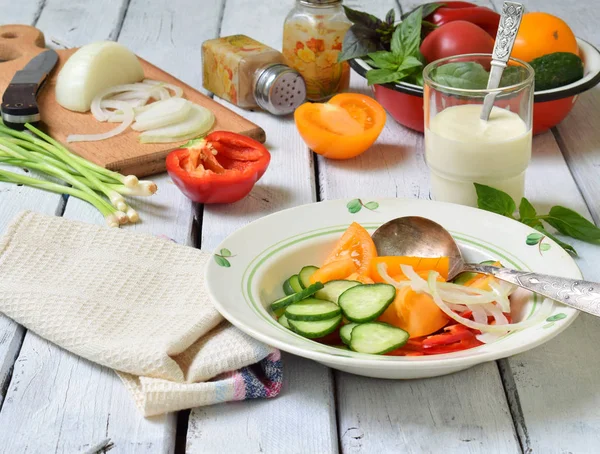 Vegetarischer, gesunder Salat mit frischem, reifem Sommergemüse: Tomaten, Gurken, Paprika und Zwiebeln auf hellem Holzgrund. — Stockfoto