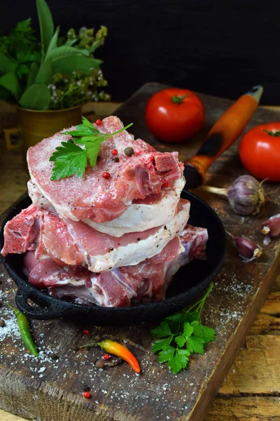 Carne cruda di maiale cosparsa di pepe nero macinato, sale e spezie in una padella di ghisa su fondo di legno. Preparazione per bistecca, arrosto, stufato. Spazio per testo . — Foto Stock