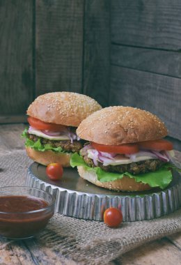 Chop patlıcan, marul, soğan turşusu, domates kahverengi ahşap arka plan üzerinde veggie burger. Vejetaryen öğle veya akşam yemeği fikir. Sağlıklı gıda.